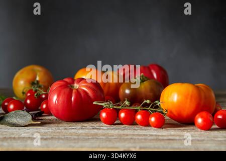 Erbstück und Kirschtomaten auf einer Holzfläche angeordnet Stockfoto