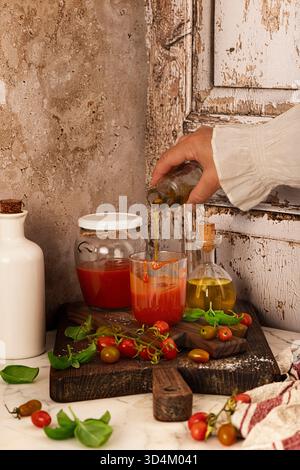 Zubereitung von hausgemachter Tomatensauce, in einer Küche, pürierte Soße in Glasbehältern, mit Olivenöl und Basilikumblättern auf einem rustikalen hölzernen B Stockfoto