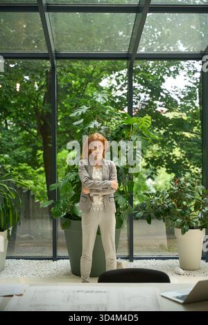 Rothaarige Frau, die mit einem Notizblock im Coworking Space steht Stockfoto
