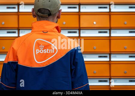 Amsterdam, Niederlande, 02.06.2025, Postangestellter von PostNL, der bei der täglichen Postzustellung in den Niederlanden neben Postfächern steht Stockfoto