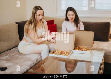 Zwei Freunde genießen überraschende Pizza zu Hause Stockfoto