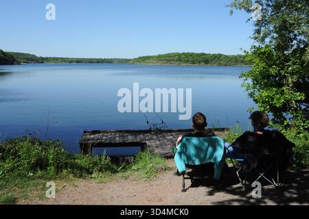 Die heitere Stute A Goriaux , ein überfluteter ehemaliger Bergbau in Nordfrankreich. Zwei Personen sitzen am Wasser, mit Angelruten, die die ruhigen Erholungsgewohnheiten der Region in ihrer industriellen Vergangenheit widerspiegeln. Mare Ã Goriaux 016955 009 Stockfoto
