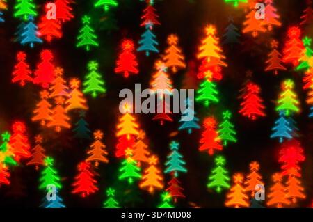 Weihnachtslichter Hintergrund mit verschwommenen weihnachtlichen festlichen mehrfarbigen Bokeh-Lichtern, leuchtenden farbigen Lichtern in Form des Weihnachtsbaums Stockfoto