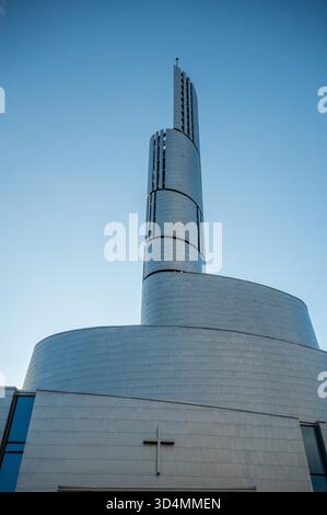 Northern Lights Cathedral, Alta, moderne Kirche mit einem markanten Spiralturm und einem Kreuz an der Fassade steht unter einem klaren blauen Himmel, vertikale Aufnahme, Norwegen Stockfoto