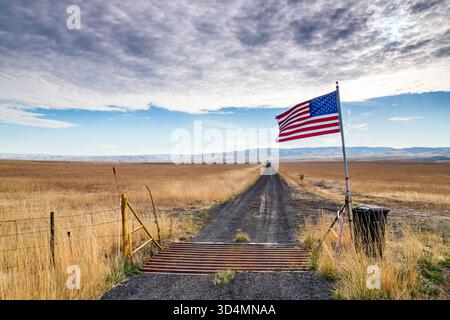 Altocumulus Wolken, US-Flagge über Feldweg zur Ranch, abseits der Yellow Jacket Road, in der Nähe der Stadt Pilot Rock, Blue Mountains Region, Oregon, USA Stockfoto