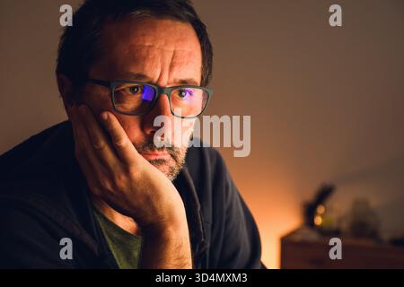 Porträt eines Reifen Mannes mit einer Brille in tiefem, warmem Licht, das tiefgründiges Denken und überdenkliches Konzept, Introspektion und geistige Ermüdung widerspiegelt. Sel Stockfoto