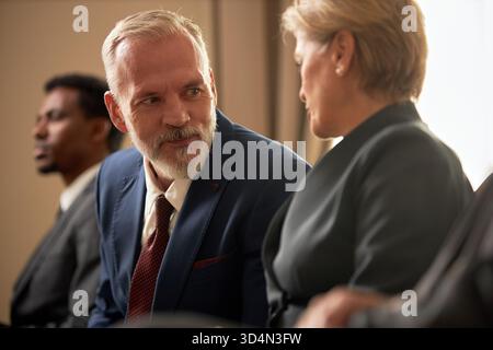 Kaukasischer Mann mittleren Alters lächelt, während er mit einer Frau mittleren Alters spricht Stockfoto