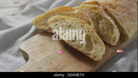 Mit geschnittenem rustikalem Brot auf Holzbrett auf Küchentisch mit hellgrauer Bettwäsche und Krümeln Stockfoto