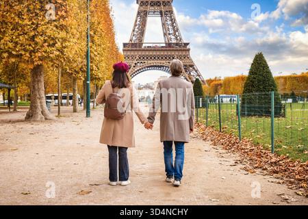 Ein romantisches Paar spaziert durch einen wunderschönen Park vor dem Eiffelturm in Paris, Frankreich, während der goldenen Herbstzeit Stockfoto