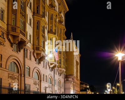 Moskau, Russland - 15. August 2025: US-Nationalflagge an der Fassade des Gebäudes der Botschaft der Vereinigten Staaten in Moskau in Russland in der Sommernacht Stockfoto