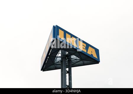 Erhöhtes blaues und gelbes Ikea-Schild auf einem hohen Metallmast gegen bewölkten Himmel. Belgrad, Serbien - 7. November 2025. Stockfoto