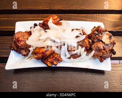 Georgianisches Lammschaschlik Mtsvadi auf weißem Teller auf Holztisch in einem lokalen Outdoor-Café in Borjomi Stadt, Georgia am Sommertag Stockfoto
