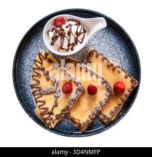 Blick von oben auf Pfannkuchen, die mit Schokoladenmuster, Erdbeeren und Eis in einer separaten Schüssel auf Keramikplatten-Ausschnitt auf weißem Hintergrund dekoriert sind Stockfoto