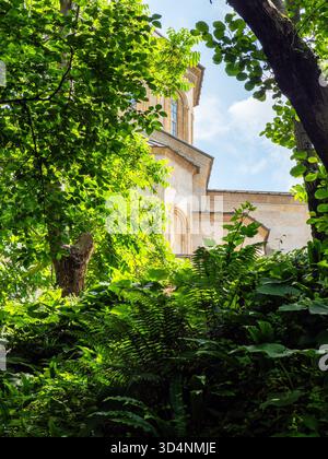 Blick auf das Gebäude der Heiligen Dreifaltigkeitskirche im Kloster Tsminda Sameba durch üppiges grünes Laub in Batumi City am sonnigen Sommertag, Georgia Stockfoto