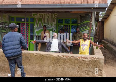 Gasura Ruanda - 8. September 2025; ein paar Männer, die Aufmerksamkeit mit Armen suchen, lachen in einer Veranda der afrikanischen Dorfbar. Stockfoto