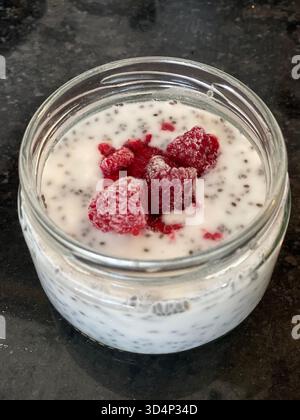 Chia Samenpudding mit gefrorenen Himbeeren auf dunklem Hintergrund. Mobiles Foto Stockfoto