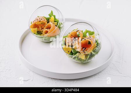 Essen, gesunder Räucherlachssalat mit gemischtem Gemüse und Sesamsamen, serviert in stilvollen Glasschalen Stockfoto
