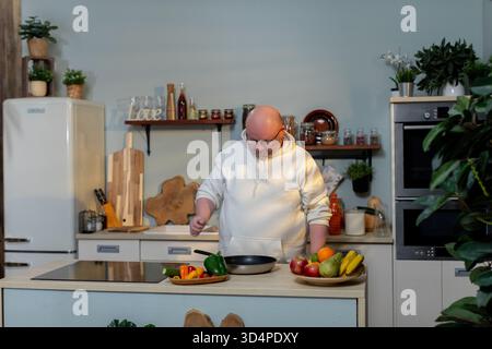 Der Küchenchef bereitet das Frühstück zu, der erfahrene Koch arrangiert Zutaten, der Küchenkünstler schneidet sorgfältig pulsierende Produkte, der ruhige Küchenchef sorgt gekonnt für frische Speisen Stockfoto