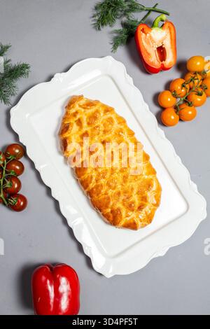Knuspriges Gebäck mit Gitteroberseite, umgeben von lebendigem Gemüse – ideal für das Branding von Comfort Food, rustikale Küchendekorationen oder Gourmet-Gerichte. Stockfoto