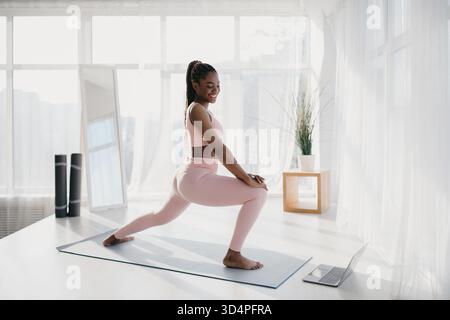 Die Junge Schwarze Frau Genießt Das Heimtraining Während Des Lockdowns, Während Sie Dem Fitness-Tutorial Folgt Stockfoto