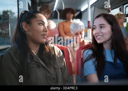 Freundinnen, die im Bus mit öffentlichen Verkehrsmitteln sprechen Stockfoto