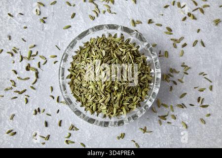 Fenchel in einer Kristallschale, verstreut auf einem grauen Betontisch, Blick von oben. Stockfoto