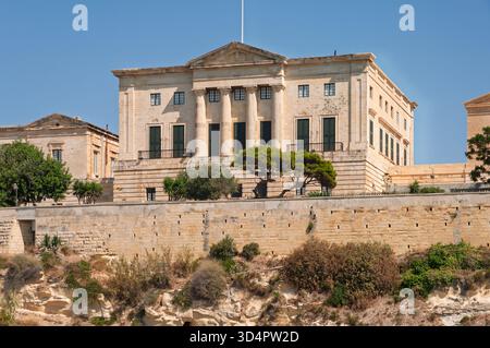 Ein großes Gebäude mit einem grünen Baum davor. Das Gebäude ist alt und hat viele Fenster Stockfoto
