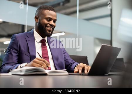 Lächelnder afroamerikanischer Geschäftsmann mit Notizbuch und Notizen Stockfoto