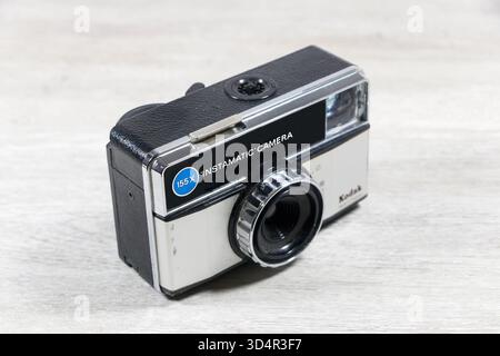 Vintage Kodak Instamatic 155X Filmkamera hergestellt in England, ausgestellt auf einer Holzoberfläche vor einem glatten weißen Hintergrund Stockfoto