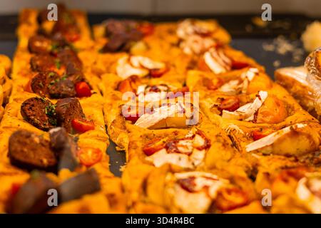Nahaufnahme verschiedener Mini-Pizzen auf einem Tablett. Dazu gehören Fleischbällchen mit Kräutern, Kirschtomaten, geschmolzener Käse und karamellisierte Zwiebeln. Golden Stockfoto