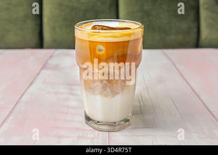 Cremiger Eiskaffee serviert in einem hohen Glas mit perfekten Schichten von kräftigem Espresso und kalter Milch auf klarem, knusprigem Eis Stockfoto