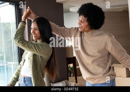 Verdrehte Paare tanzen im modernen Wohnzimmer, mit Umzugskästen und Glasschiebetür Stockfoto