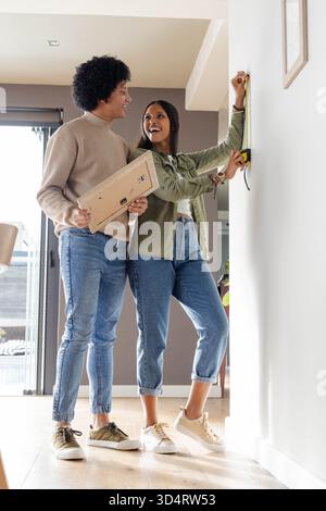 Verschiedene Maßwand für Paare in hellem Wohnzimmer, mit gelbem Maßband und Rahmenrücken Stockfoto