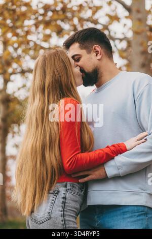 Romantischer Spaziergang auf dem parkside mit pelzigen Begleitern, Liebhaber, die sich auf einem grünen Pfad mit einem kleinen Hund in der Nähe umschließen Stockfoto
