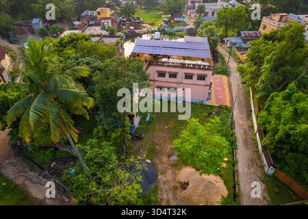 Drohnenansicht der Installation von Solarpaneelen auf dem Dach in Wohngebäuden, umgeben von grünen Bäumen im Vorort Indiens. Stockfoto