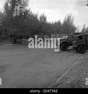 Ein archiviertes Schwarzweißfoto aus den 1970er Jahren zeigt eine Reihe von spezialisierten sowjetischen Lkws im Öllager Sloviansk, der ukrainischen SSR. Neben einem Geländefahrzeug GAZ-66 steht ein Feuerwehrwagen ZIL-131 mit großem Schaummonitor auf dem Dach. Diese Einsatzfahrzeuge sind in der Nähe der Tankstelle des Depots stationiert, die im Hintergrund sichtbar ist. Diese Szene verdeutlicht das hohe Maß an Sicherheitsvorsorge an der Industriestelle im friedlichen Donbass. Stockfoto