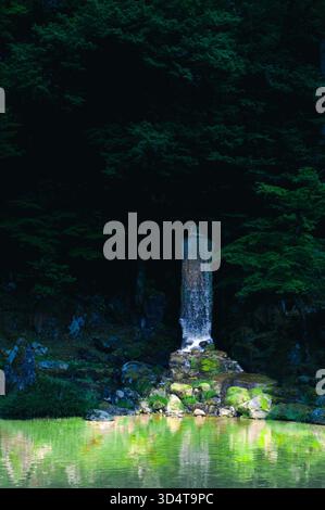 Kleiner Wasserfall, der über moosige Steine fließt, im Kenrokuen Garden, Japan. Stockfoto