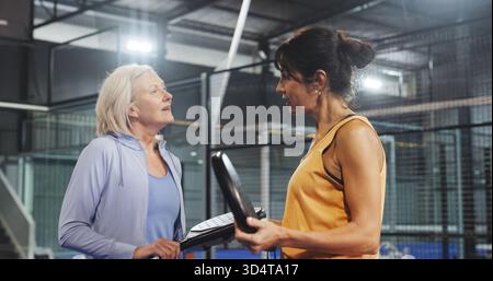 Padel, Sprechen und Fitness mit Freunden auf dem Platz für Training, Turnierclub und Challenge. Sportlerin, Diskussion und Gesundheit mit Reifen Frauen Stockfoto
