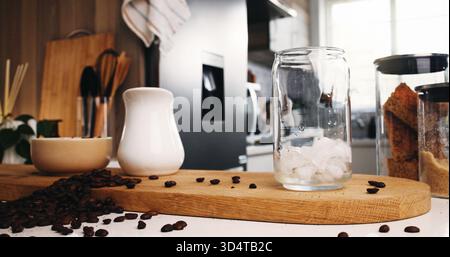 Eis, Kaffee und Glas auf dem Tisch in der Küche zu Hause für Koffein-Getränk, Frühstück und morgendliches Brauen. Cappuccino, kalter Latte-Drink und mit einer Tasse zubereiten Stockfoto