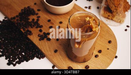 Spritzer, Kaffee und Glas auf dem Tisch in der Küche zu Hause für Koffein-Getränk, Frühstück und Morgengebräu. Cappuccino, Eiskaffee-Latte-Getränk und Zubereitung mit Stockfoto