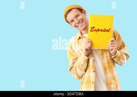 Junger Mann mit Buch auf blauem Hintergrund. Spanisch Lernen Stockfoto