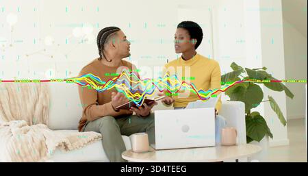 Besprechung von 2 Kollegen in braunem Pullover und gelbem Oberteil, Überprüfung der Daten auf Sofa mit Laptop-Overlay Stockfoto