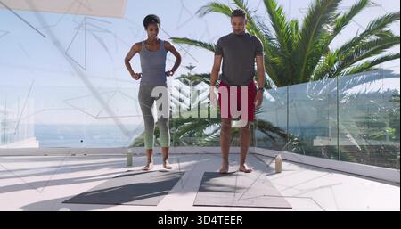Stretching-Workout-Partner in Sportbekleidung auf der Küstenterrasse mit Yoga-Matten und Wasser Stockfoto