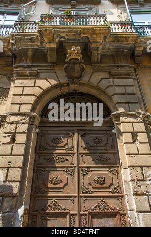 Monumentaler Eingang des barocken Palazzo Cattolica aus dem 18. Jahrhundert in Palermo, Sizilien, Italien. Verzierte Doppeltüren aus Eisen mit dekorativem Scrollwerk Stockfoto