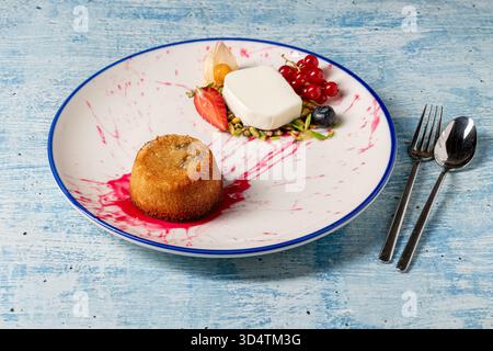 Warmes Tahini-Souffle-Dessert mit Eis und gemischten Beeren auf einem Teller Stockfoto