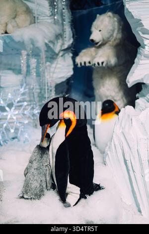 Üppige Kaiserpinguine und Eisbären in einem verschneiten Einzelhandelsgeschäft mit Eishöhle und Schneeflockendekor. Winterthema mit Tierwelt. Warschau, Polen Stockfoto