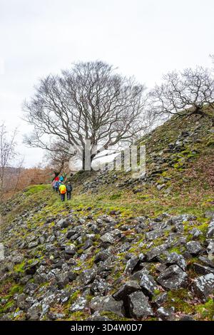 Eine Gruppe von Wanderern, die auf einem felsigen Fußweg spazieren, schneidet in einem Hügel im Derbyshire Peak District nahe Baslow. Stockfoto