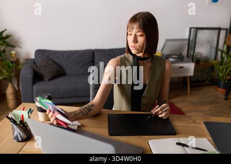 Junge Frau konzentriert sich auf ihre kreativen Projekte zu Hause, umgeben von Pflanzen und Kunstbedarf. Stockfoto