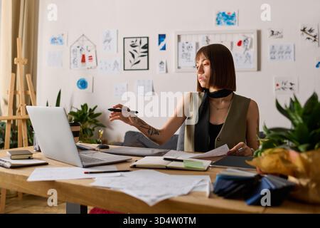 Junge Frau engagiert sich zu Hause in künstlerischen Projekten, entwirft Entwürfe und erforscht Ideen. Stockfoto