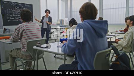 Konzentrierte Schüler Hören Sie dem Lehrer zu, der die Aufgabe der Codierung erklärt. Die Schüler sitzen aufmerksam an den Schreibtischen und folgen den Erläuterungen der Lehrer zu Programmierkonzepten. Konzept der digitalen Bildung. Dolly Shot. Stockfoto